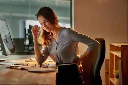 Женщина сидит за столом и болит спина