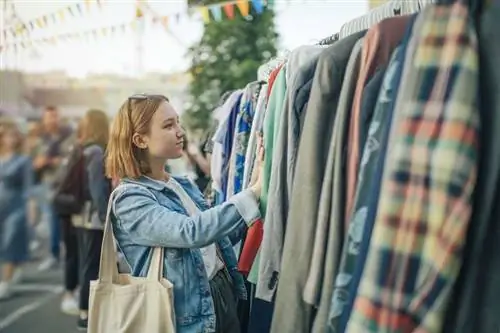 Женщина с джутовым мешком стоит перед вешалкой для одежды Женщина с джутовым мешком стоит перед вешалкой для одежды