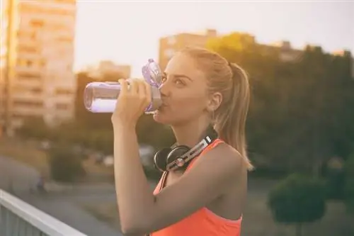 Спортсменка пьет воду во время тренировки