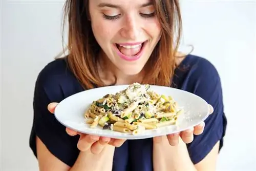 Женщина держит тарелку макарон