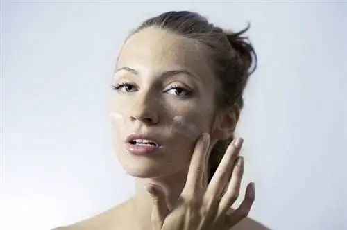 Женщина наносит крем на лицо