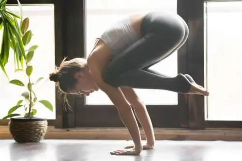 Женщина занимается йогой в позе вороны