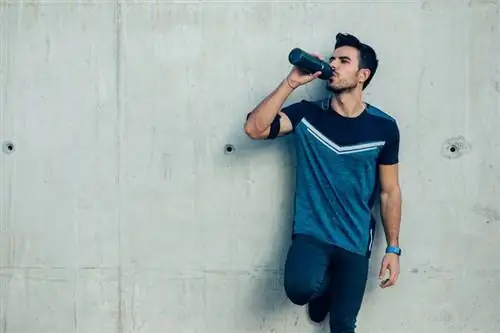 Мужчина пьет из спортивной бутылки Мужчина пьет из спортивной бутылки