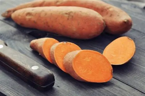 Сладкий картофель лежит разрезанный рядом с ножом Сладкий картофель лежит разрезанный рядом с ножом