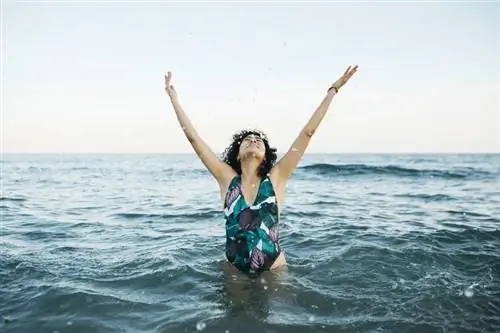 Женщина стоит в море и радуется
