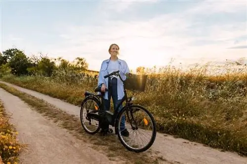 Женщина стоит рядом со своим велосипедом