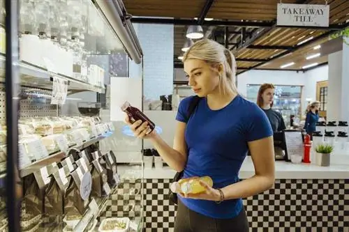 Женщина смотрит на мобильный телефон во время покупок