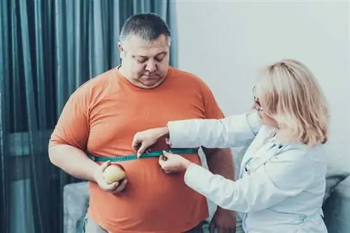 Мужчине с избыточным весом измеряют талию Мужчине с избыточным весом измеряют талию