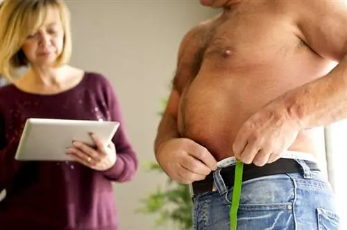 Мужчина измеряет окружность талии