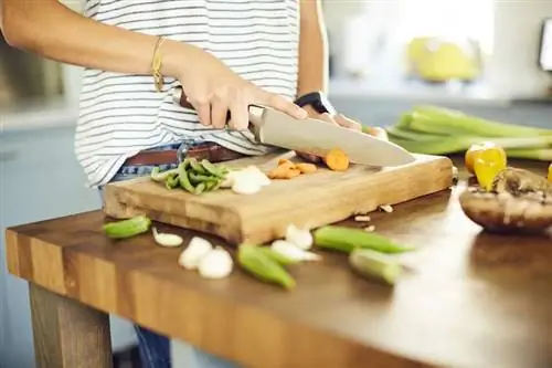 Женщина режет овощи на деревянной доске