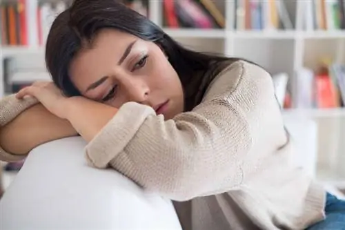 Грустная женщина сидит на диване