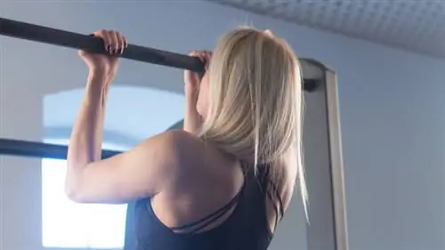 человек с длинными волосами в спортзале выполняет подтягивания