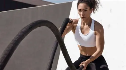 Длинноволосый человек делает упражнения с боевой веревкой на открытом воздухе