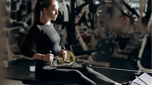 Женщина в тренажерном зале выполняет упражнения на канатной тяге