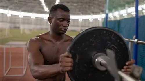 Мужчина загружает штангу блином