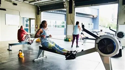 Женщина использует гребной тренажер в тренажерном зале CrossFit