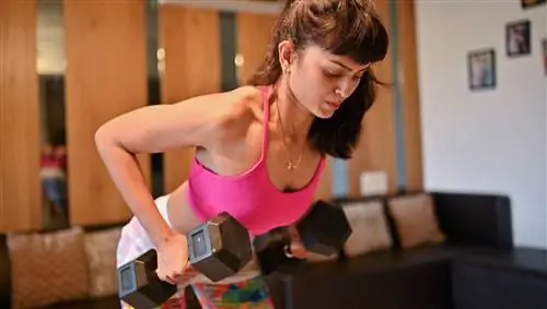 Женщина выполняет тягу гантелей в наклоне