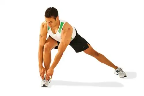 Мужчина выполняет боковой выпад, касаясь одной ноги обеими руками