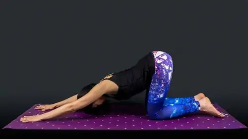 Женщина-учитель йоги в позе щенка изолирована на черном фоне