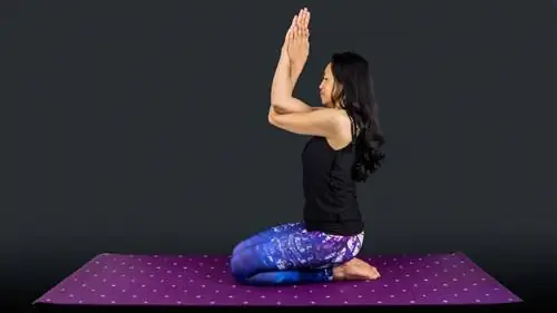 Женщина-учитель йоги в позе Ваджрасана Гарудасана изолирована на черном фоне