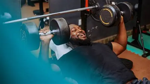 Мужчина выполняет жим гантелей на наклонной скамье