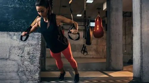 Женщина выполняет жим груди TRX