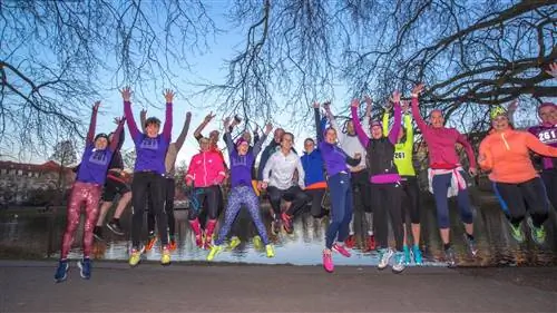 Группа женщин в беговой экипировке прыгает в унисон