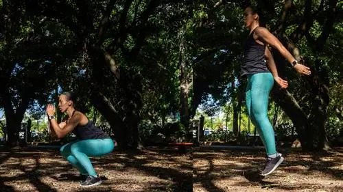 Женщина выполняет приседания с прыжками в парке