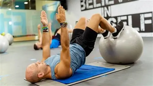 Мужчина выполняет сгибание подколенных сухожилий на спортивном мяче