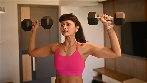 Женщина держит гантели за головой