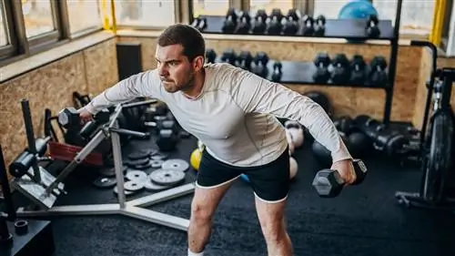 Мужчина выполняет боковой подъем с гантелями