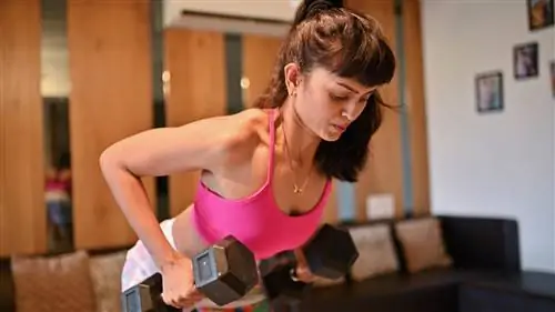 Женщина выполняет тягу гантелей в наклоне