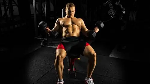 Мужчина выполняет подъем гантели под углом 45 градусов на наклонной скамье